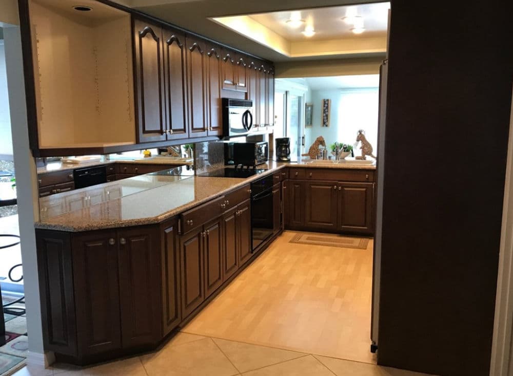 Modern kitchen with dark wood cabinets, granite countertops, and stainless steel appliances.